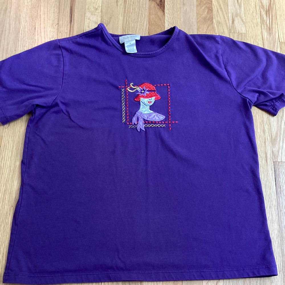 - purple shirt with an embroidered picture (lady with a red hat)